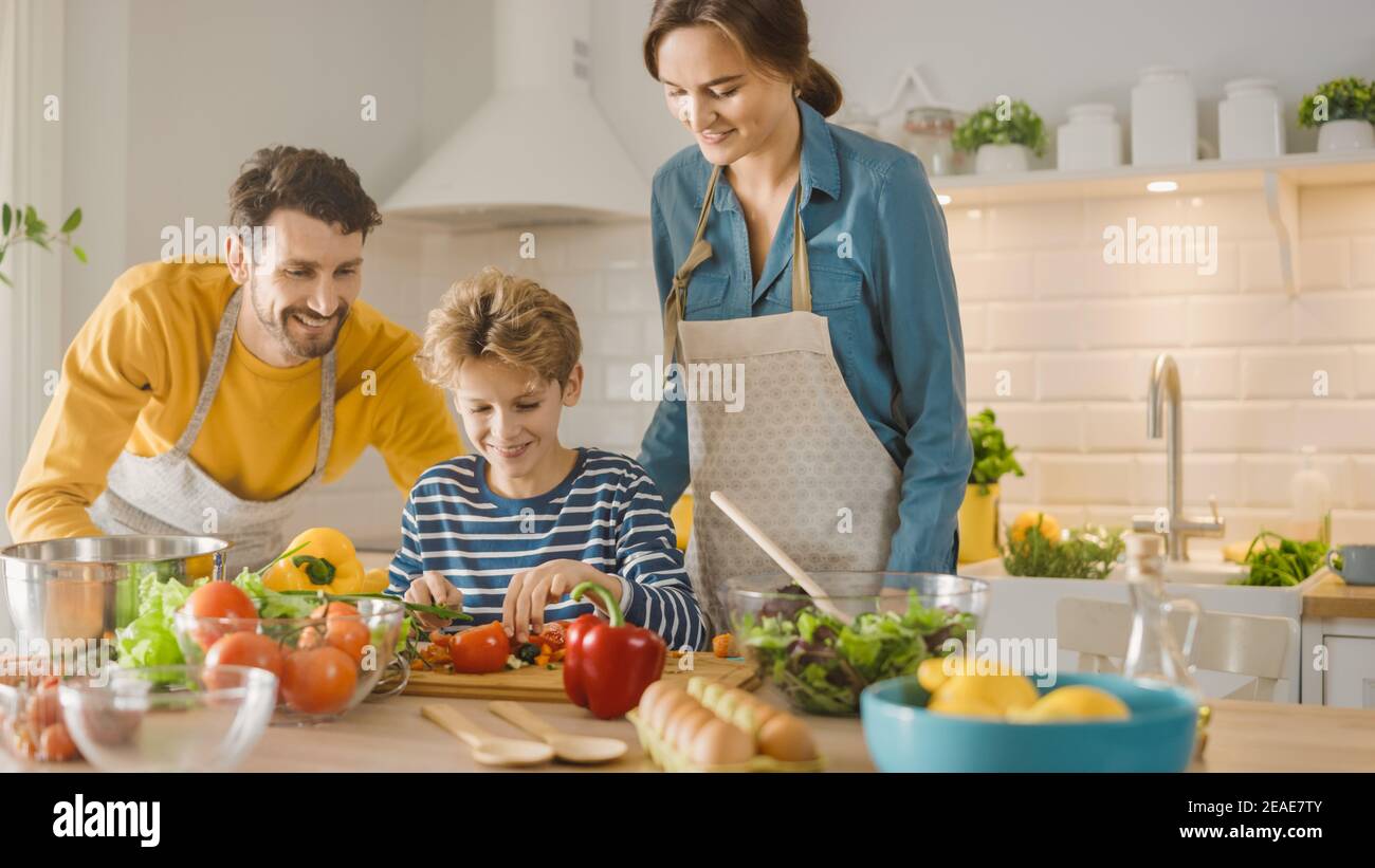 In der Küche: Familie von drei Kochen zusammen gesundes Abendessen. Mutter und Fathin lehren Little Boy gesunde Gewohnheiten und Gemüse für das Abendessen Salat schneiden Stockfoto