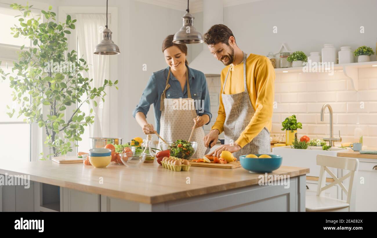 In der Küche: Perfekt glückliches Paar gesunde Lebensmittel vorbereiten, viel Gemüse. Mann jongliert mit Früchten, bringt ihre Freundin zum Lachen. Nette Leute Stockfoto