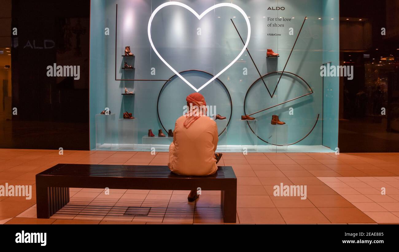 Emirati Mann sitzt auf Holzbank im Inneren der Mall, und Herz auf Hintergrund geformt Stockfoto