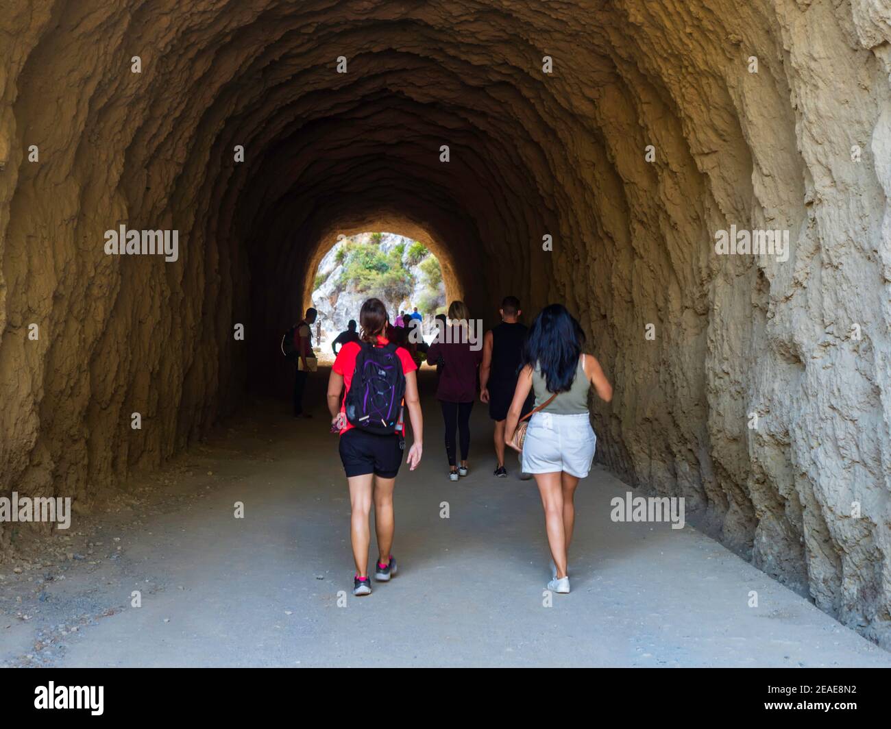 Zwei Frauen, die an einem sonnigen Tag durch einen Tunnel in den Bergen des Naturparks der Gaitanes-Schlucht in Malaga fahren. Stockfoto