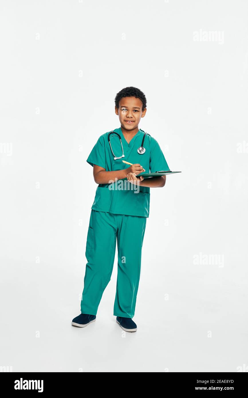 Afroamerikanisches männliches Kind schreibt medizinische Behandlung auf seine Zwischenablage. Weißer Hintergrund Stockfoto
