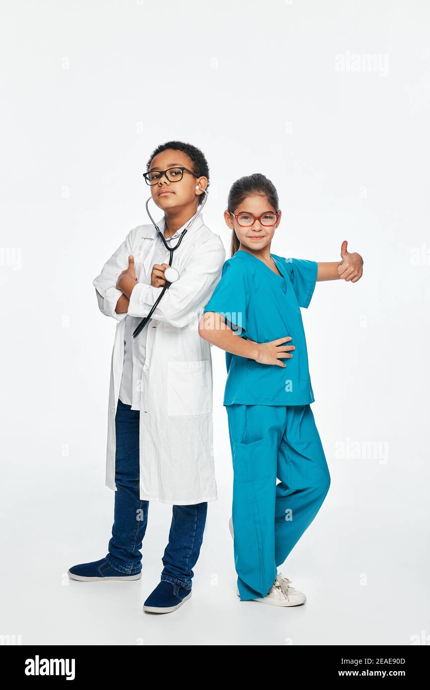 Glückliche multiethnische Kinder spielen den medizinischen Beruf. Isoliert auf weißem Hintergrund, volles Wachstum Stockfoto