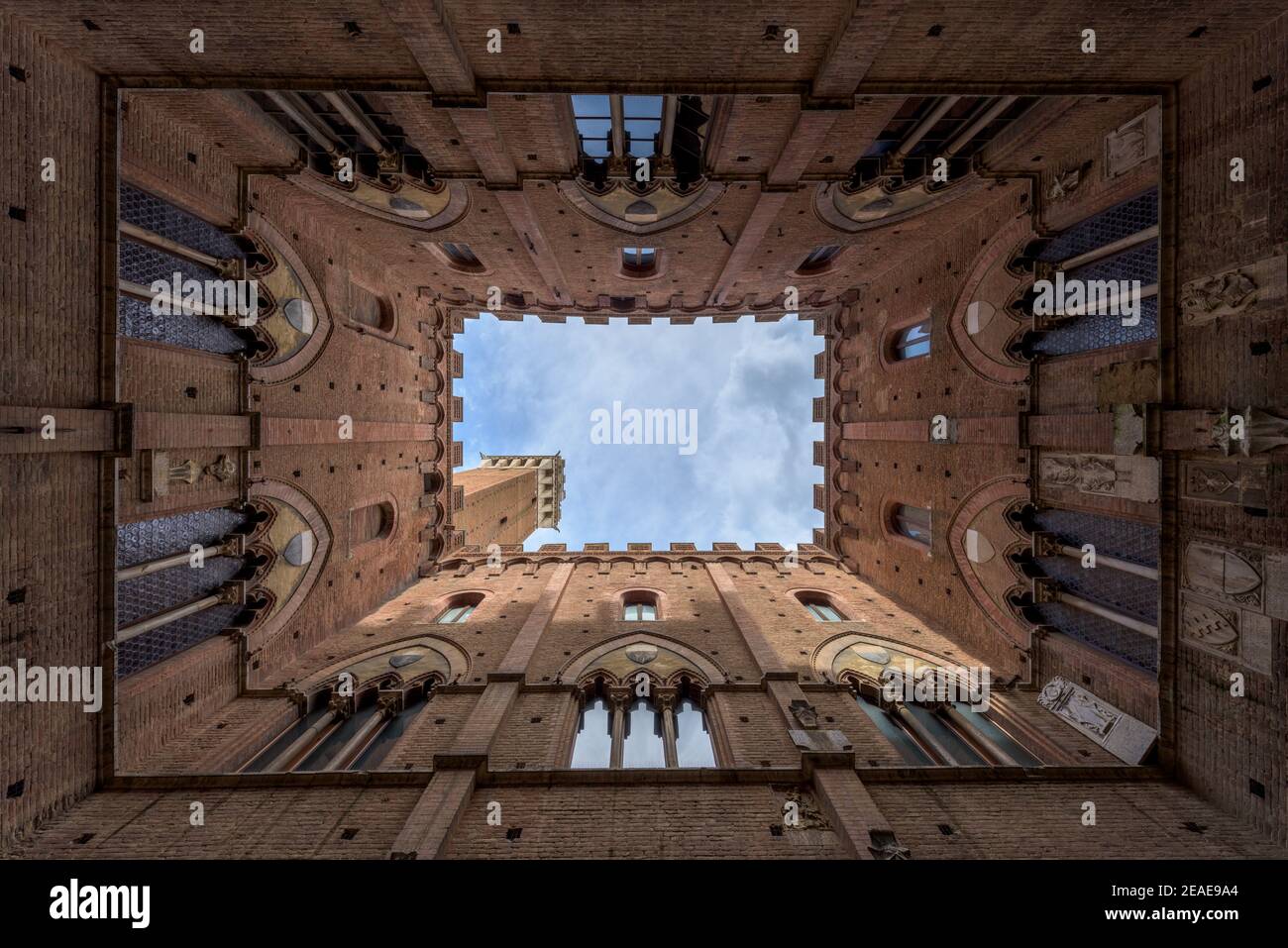 Von unten nach oben vertikale Ansicht des Innenhofes im Palazzo Pubblico, einem mittelalterlichen Rathausgebäude auf dem Hauptplatz der Altstadt von Siena in der Toskana, Stockfoto