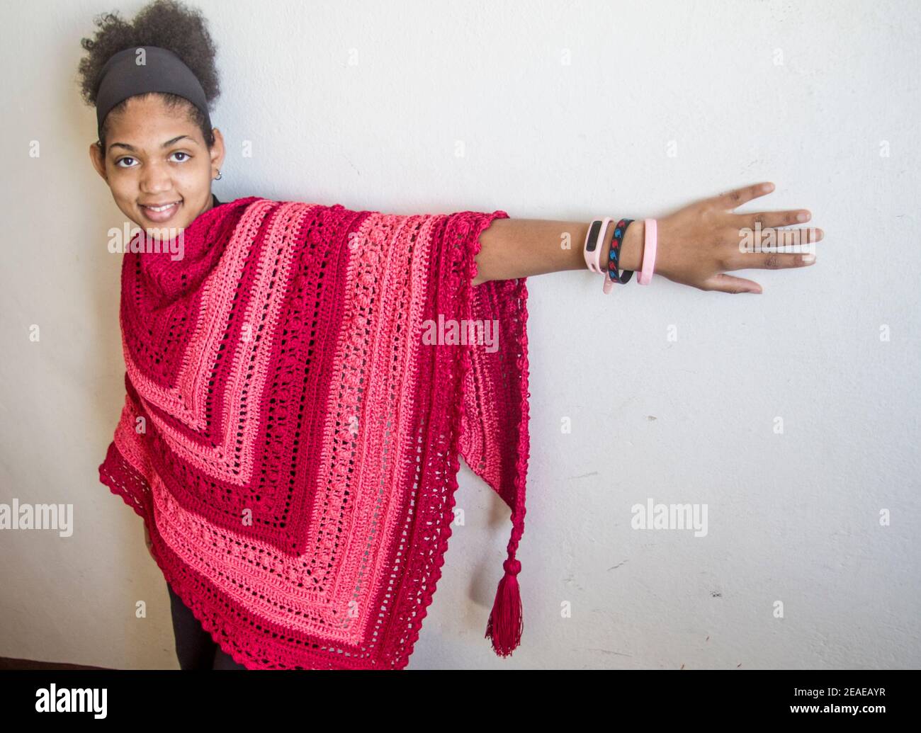 Eleganter roter und rosa Poncho oder Schal von einem gebunden Junge lächelnd und glücklich brasilianischen Modell Stockfoto