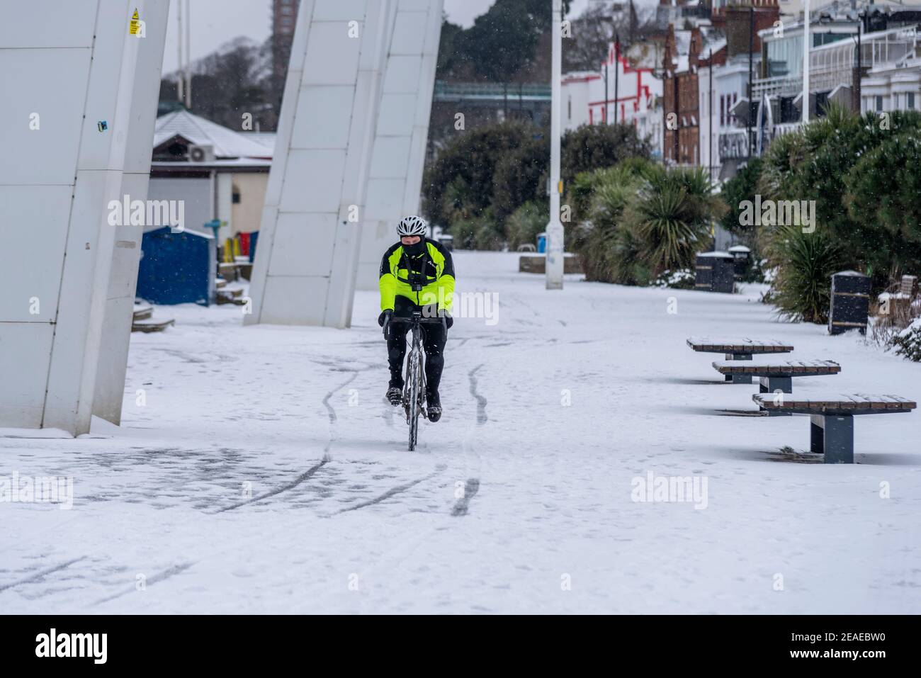 Southend on Sea, Essex, Großbritannien. Februar 2021, 9th. Storm Darcy hat an der Strandpromenade weiteren Schnee fallen gelassen und eisige und windige Bedingungen gebracht. Jogger und Spaziergänger trotzten der Kälte und dem Wind. Ein Radfahrer auf der Strandpromenade Marine Parade Stockfoto