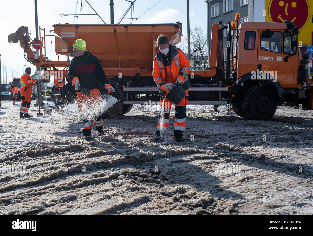 Dortmund, Deutschland. Februar 2021, 09th. Mitarbeiter des öffentlichen Nahverkehrsbetreibers DSW21 verteilen an einer Kreuzung Salz auf freie Straßenbahngleise vor Schnee an einer Kreuzung. Quelle: Bernd Thissen/dpa/Alamy Live News Quelle: dpa picture Alliance/Alamy Live News Stockfoto