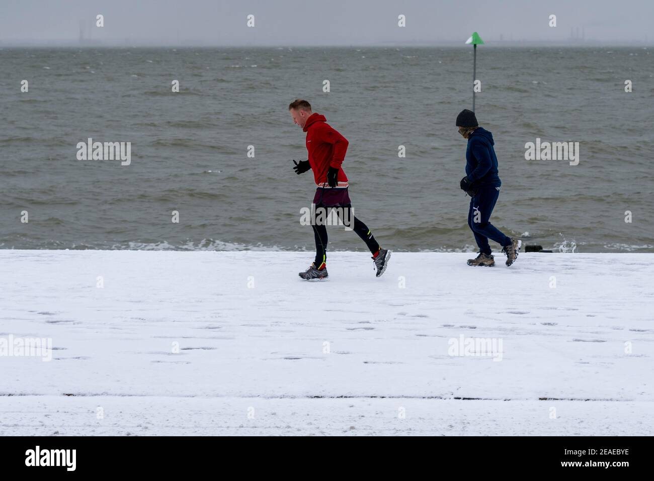 Southend on Sea, Essex, Großbritannien. Februar 2021, 9th. Storm Darcy hat an der Strandpromenade weiteren Schnee fallen gelassen und eisige und windige Bedingungen gebracht. Jogger und Spaziergänger trotzten den kalten Winden entlang der Western Esplanade am Meer Stockfoto