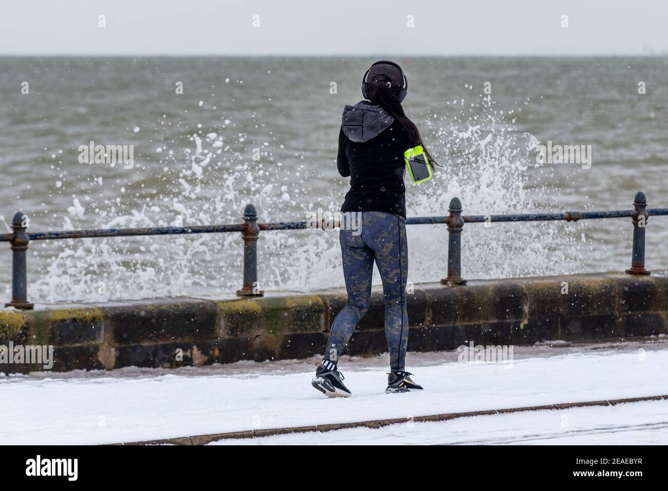 Southend on Sea, Essex, Großbritannien. Februar 2021, 9th. Storm Darcy hat an der Strandpromenade weiteren Schnee fallen gelassen und eisige und windige Bedingungen gebracht. Jogger und Spaziergänger trotzten den kalten Winden und stürzenden Wellen entlang der Western Esplanade Stockfoto