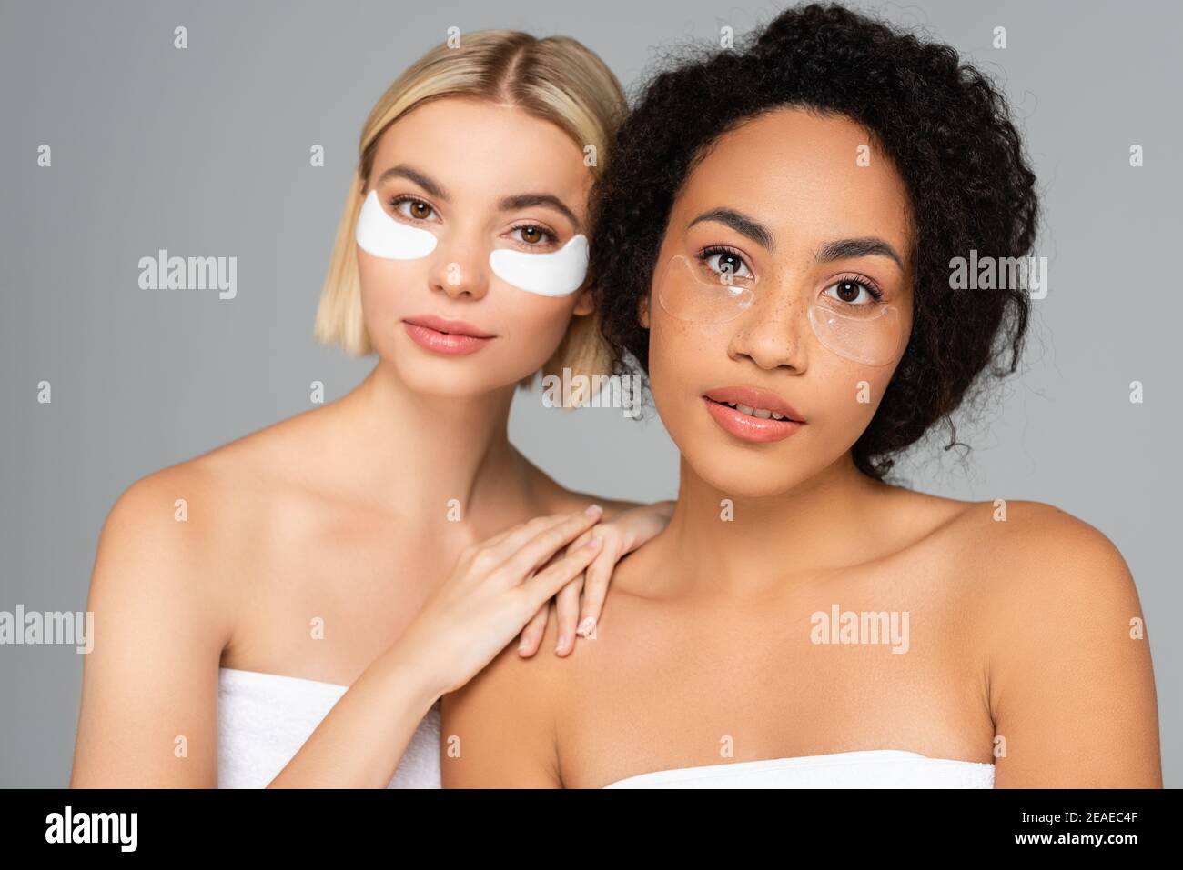 Junge multiethnische Frauen mit perfekten Haut-und Augenflecken isoliert Auf Grau Stockfoto