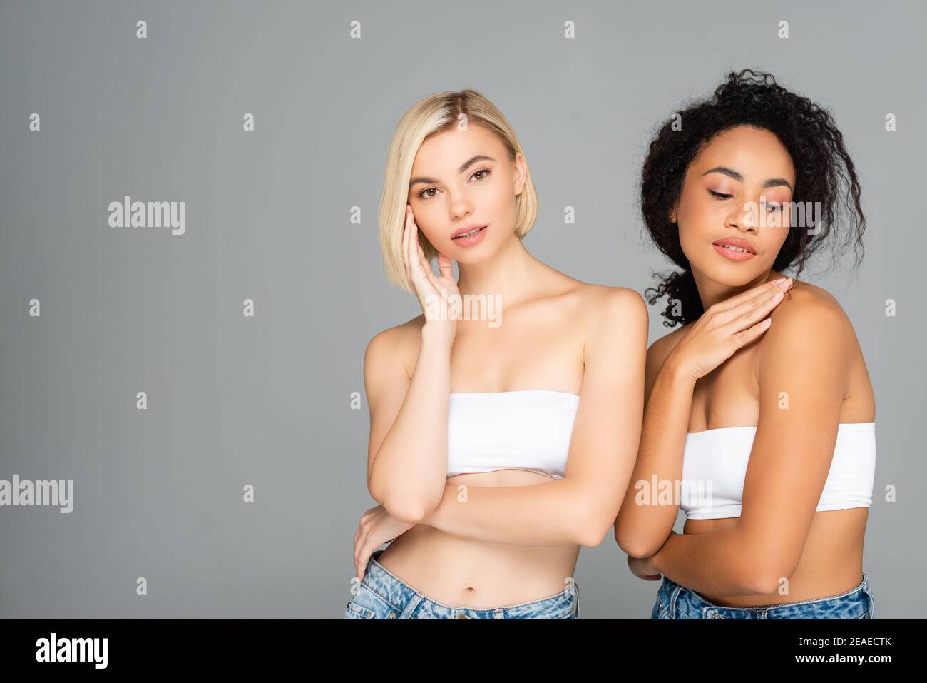 Junge interracial Frauen mit perfekter Haut posiert isoliert auf grau Stockfoto