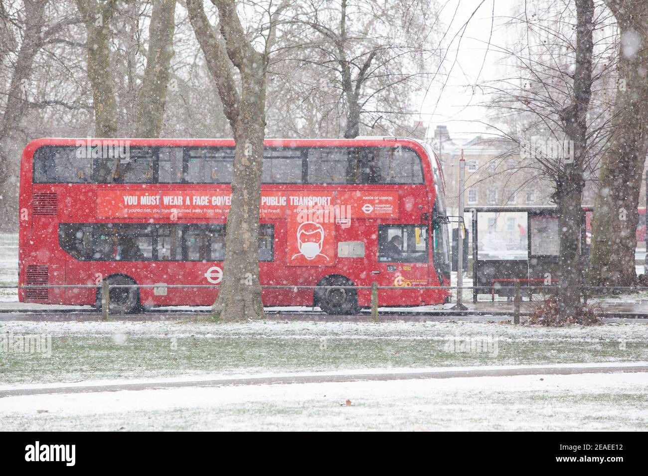 London, Großbritannien. 9. Februar 2021: Nach drei Tagen Schnee in London beginnt es sich zu beruhigen und die Winde sind gefallen, als Storm Darcy vorbei ist. Auf Clapham Common nehmen einige Leute Übung und vorbeifahrende Busse tragen Nachrichten über das Tragen von Gesichtsbedeckungen. Quelle: Anna Watson/Alamy Live News Stockfoto