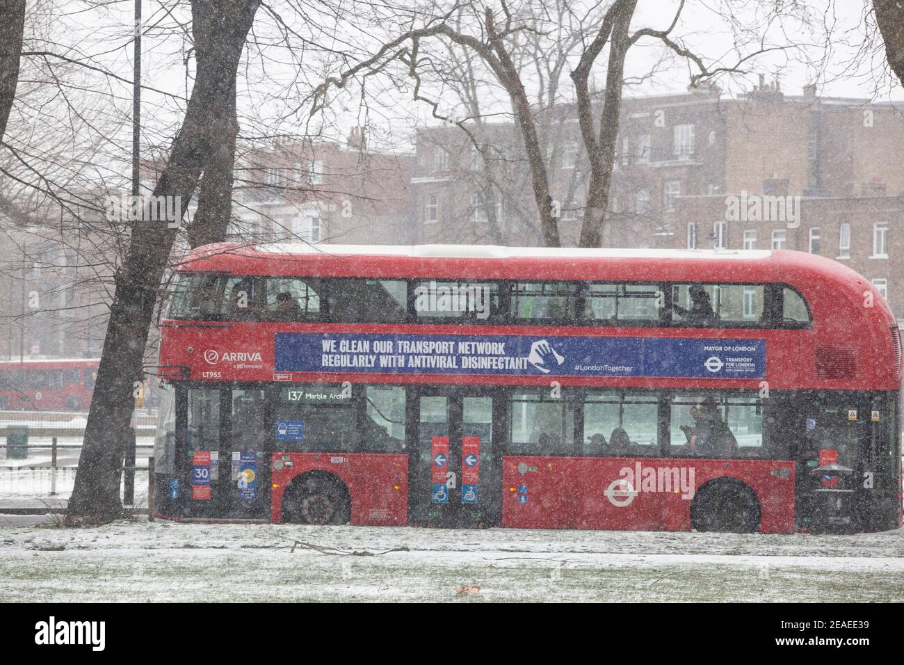 London, Großbritannien. 9. Februar 2021: Nach drei Tagen Schnee in London beginnt es sich zu beruhigen und die Winde sind gefallen, als Storm Darcy vorbei ist. Auf Clapham Common nehmen einige Leute Übung und vorbeifahrende Busse tragen Nachrichten über das Tragen von Gesichtsbedeckungen. Quelle: Anna Watson/Alamy Live News Stockfoto