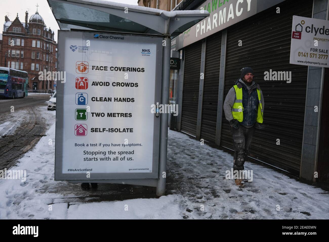 Glasgow, Großbritannien, am 9. Februar 2021. Fußgänger machen ihren Weg zur Arbeit, vorbei an öffentlichen Informationstafeln über die laufende Covid-19 Coronavirus-Gesundheitspandemie. Foto: Jeremy Sutton-Hibbert/ Alamy Live News. Stockfoto
