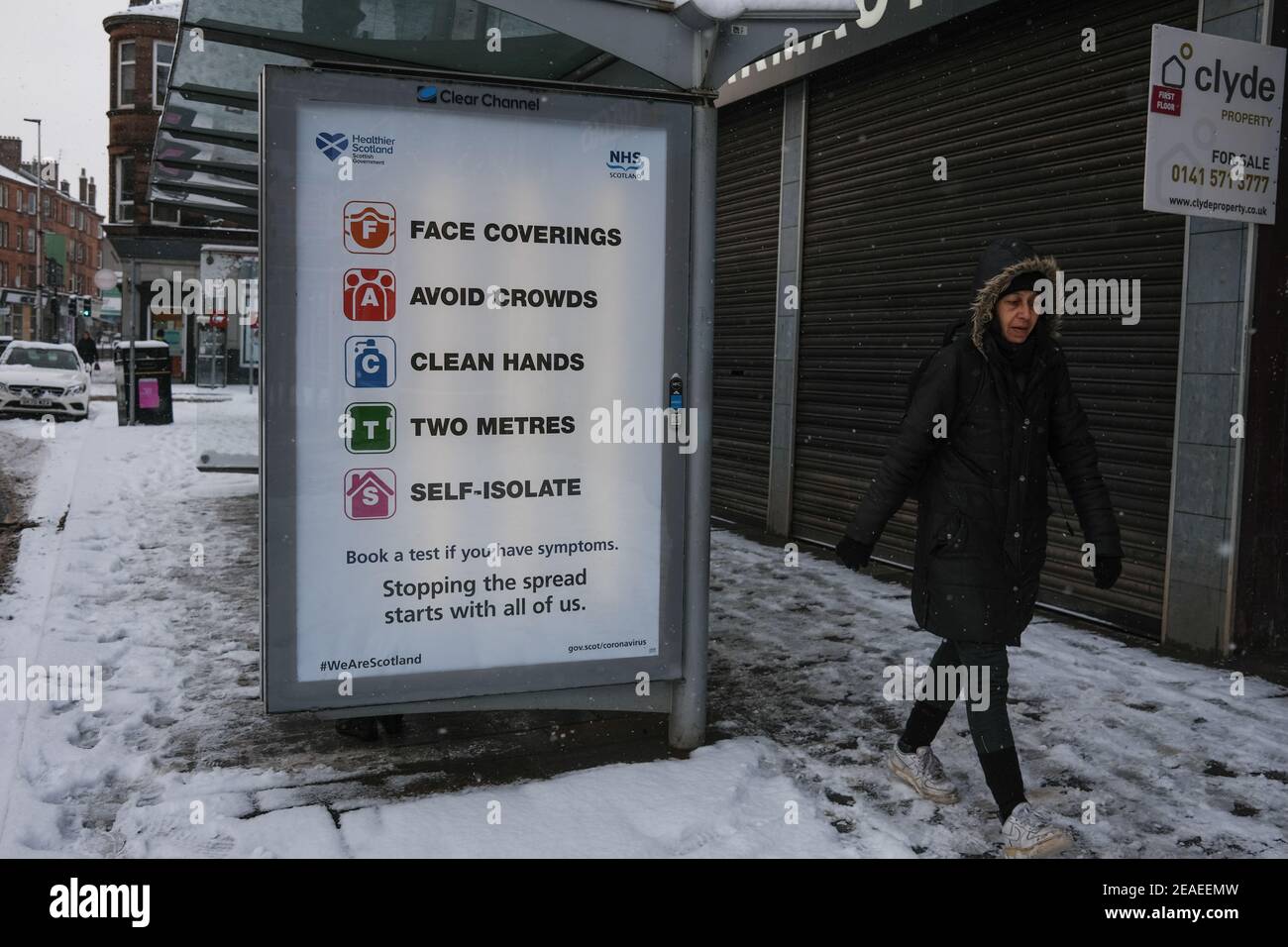 Glasgow, Großbritannien, am 9. Februar 2021. Fußgänger machen ihren Weg zur Arbeit, vorbei an öffentlichen Informationstafeln über die laufende Covid-19 Coronavirus-Gesundheitspandemie. Foto: Jeremy Sutton-Hibbert/ Alamy Live News. Stockfoto