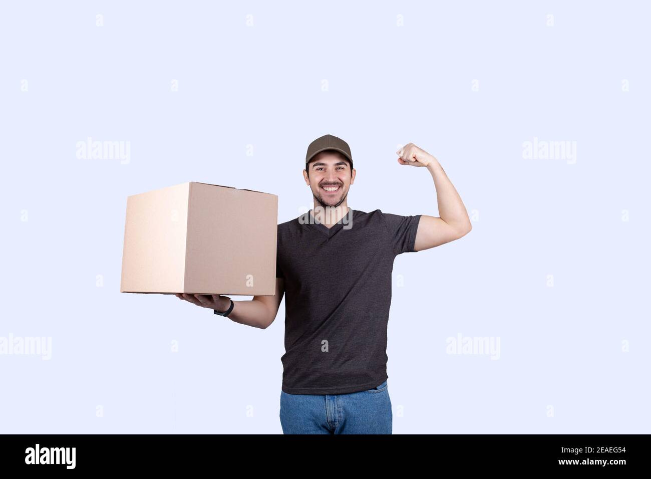Happy Delivery Mann hält eine Box-Paket und felxing eine Hand Bizeps vorstellen Superpower. Selbstbewusster Kurierarbeiter . Persönliche Entwicklung, Kraft und m Stockfoto
