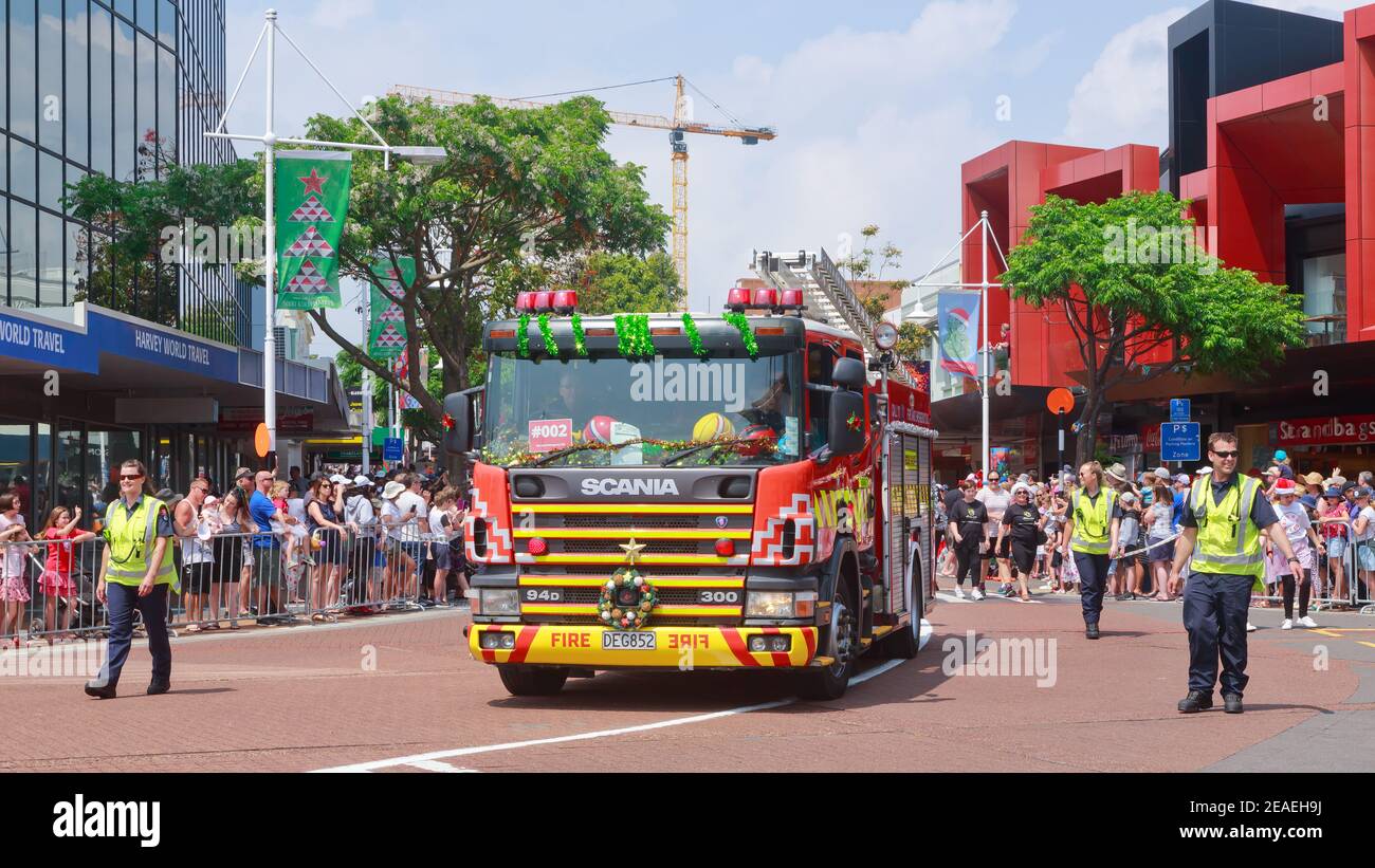 Ein dekorierter Feuerwehrmann, begleitet von Feuerwehrleuten, der an einer Weihnachtsparade in Tauranga, Neuseeland, teilnimmt Stockfoto