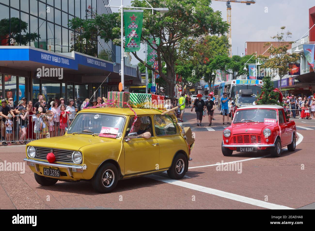 Klassische Mini-Autos, die an einer Weihnachtsparade in Tauranga, Neuseeland, teilnehmen, geschmückt mit Geschenken und einem Weihnachtsbaum Stockfoto