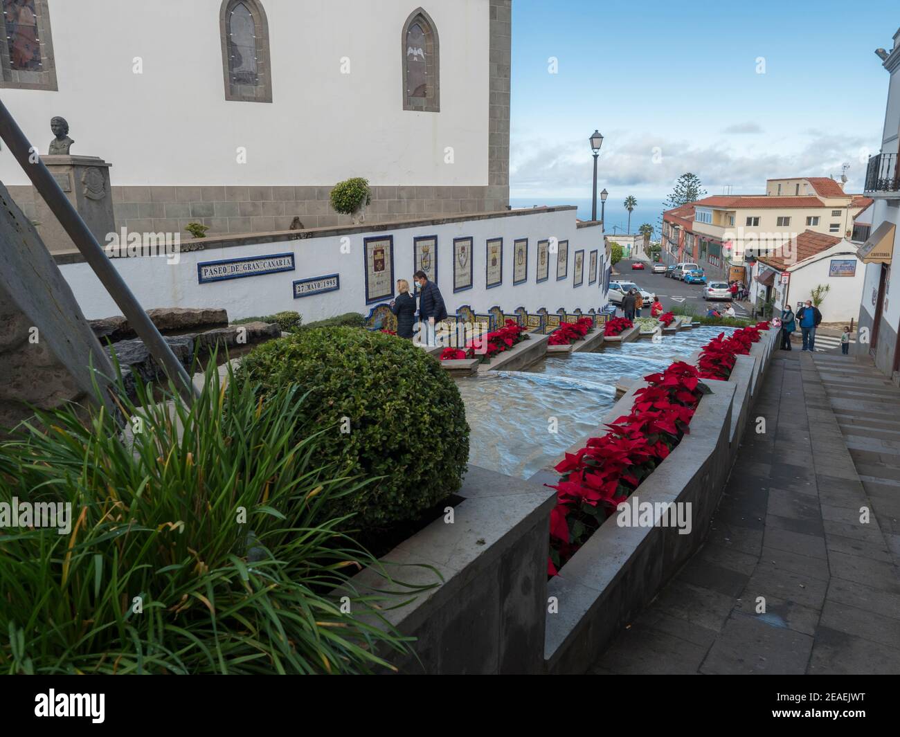 Firgas, Gran Canaria, Kanarische Inseln, Spanien 13. Dezember 2020: Blick auf die Straße Paseo de Gran Canaria mit Wasserfall Brunnen, Blumen und Keramik Stockfoto