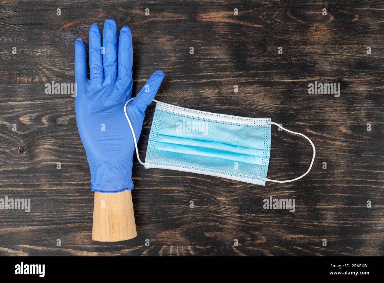 Schaufensterpuppe Hand trägt einen Einweghandschuh und hält eine medizinische Maske. Während der Quarantäne von covid19. Stockfoto