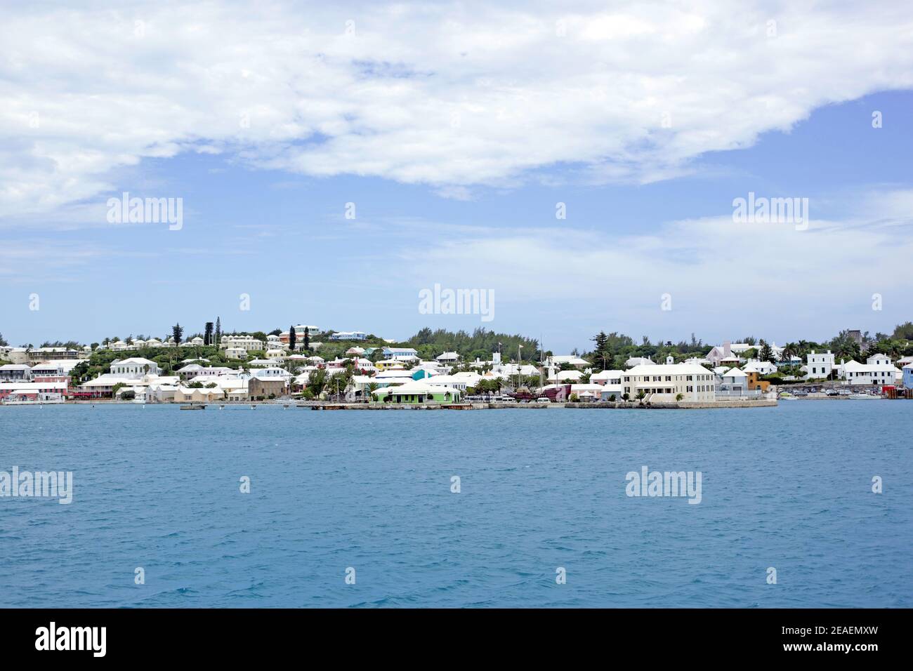 Blick auf die Uferpromenade, Saint George's, die von pastellfarbenen Gebäuden mit weißen Dächern, ruhigen blauen Ozean und blauen Himmel mit Wolken gekennzeichnet ist. Stockfoto