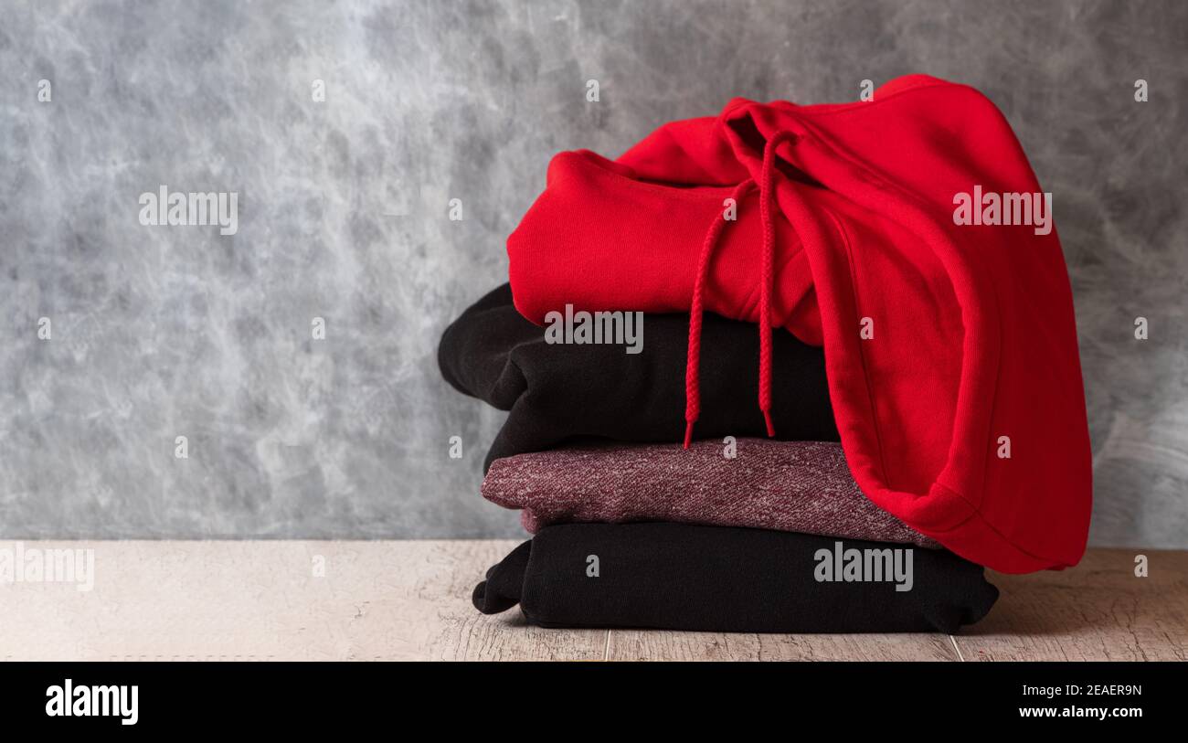 Stapel von Kapuzenpullover und Hoodie auf grauem Hintergrund. Speicherplatz kopieren Stockfoto