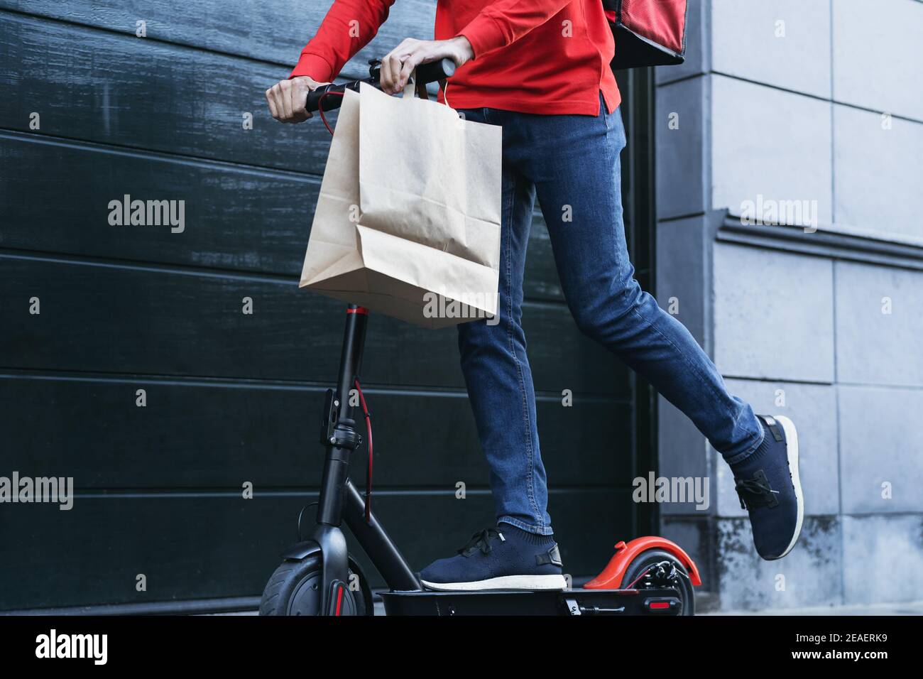 Fahrer Mann liefern Mahlzeit an Kunden mit Elektroroller - Ökologisches Fast Delivery Food Konzept Stockfoto