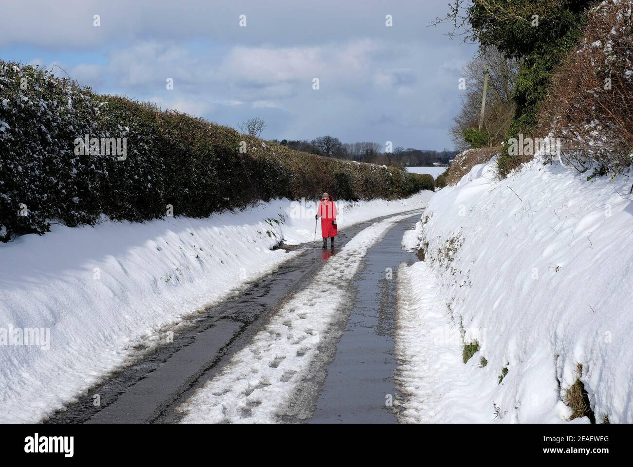 Ältere Person, die auf einer schneebedeckten Landstraße, melton Stable, Nord-norfolk, england, läuft Stockfoto