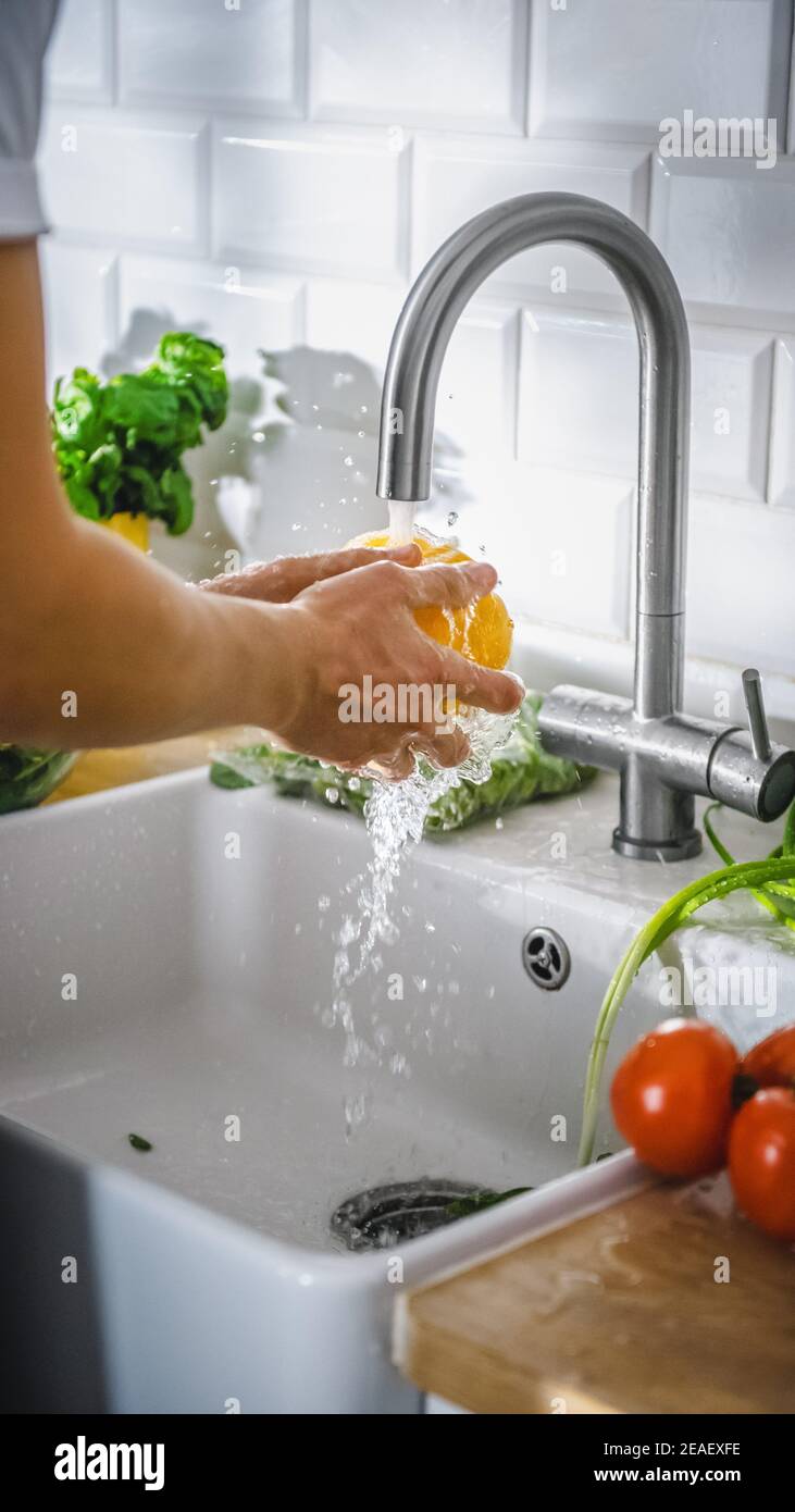 Nahaufnahme Aufnahme einer Person, die mit Leitungswasser gelben, süßen Pfeffer wäscht. Authentische stilvolle Küche mit gesundem Gemüse. Natürliche saubere Produkte von Stockfoto