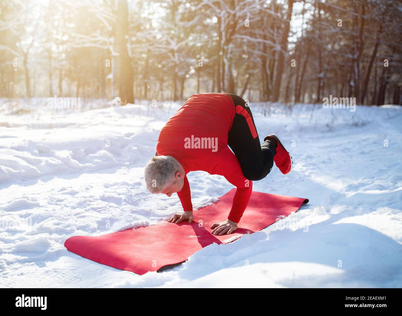 Fit Senior Mann mit Outdoor-Yoga-Praxis im Winter an Verschneite Wälder Stockfoto