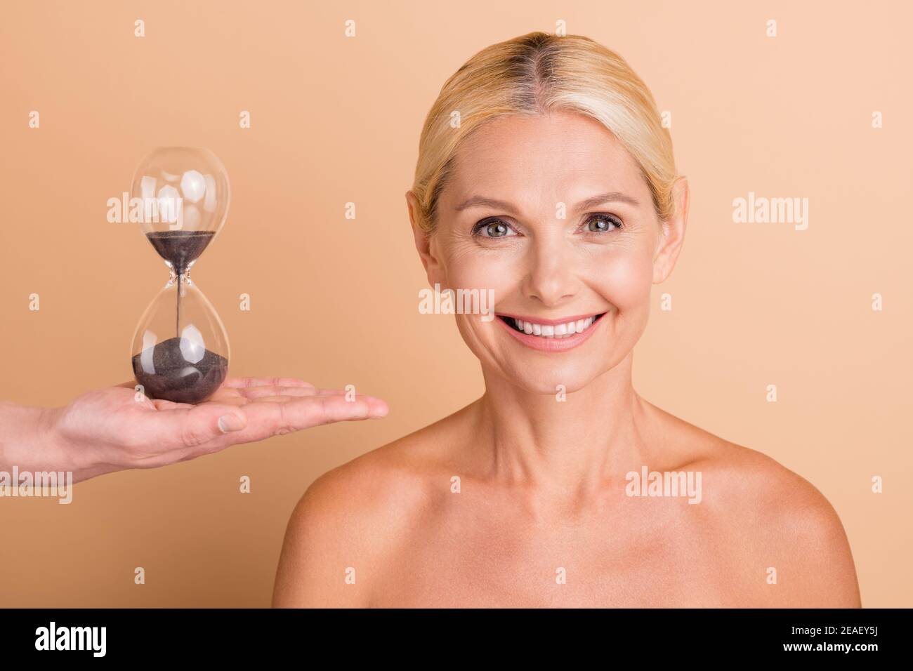 Portrait of Harmony Frau mittleren Alters genießen Hautpflege Spa Salon Verfahren Sandglas Uhr isoliert Farbe Hintergrund Stockfoto