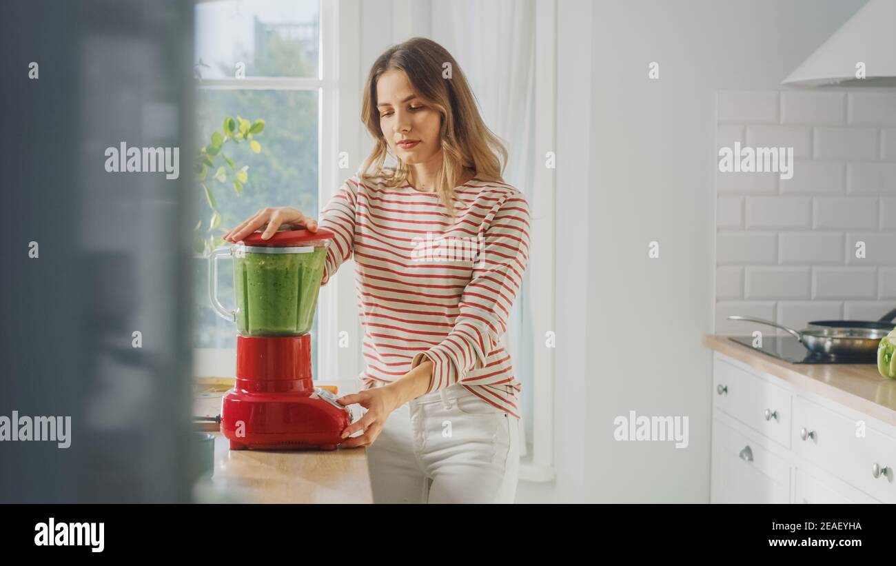 Schöne junge Frau Vorbereitung einer gesunden grünen Smoothie in einem Blender. Authentische stilvolle Küche mit gesundem Gemüse. Natürliche saubere Produkte von Stockfoto