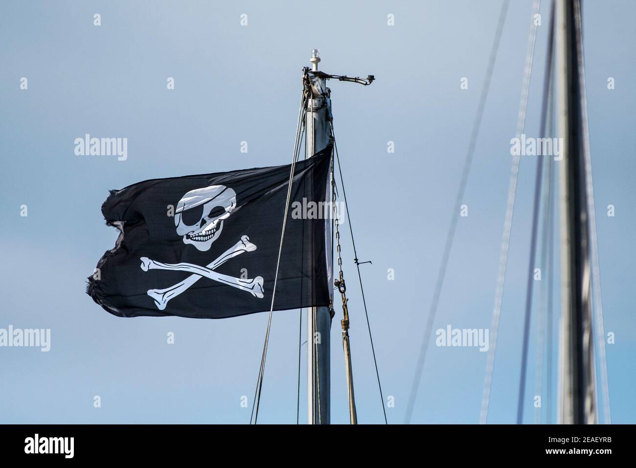 Eine Skull- und Crossbones-Flagge, die vom Mast eines Bootes aus fliegt. Stockfoto