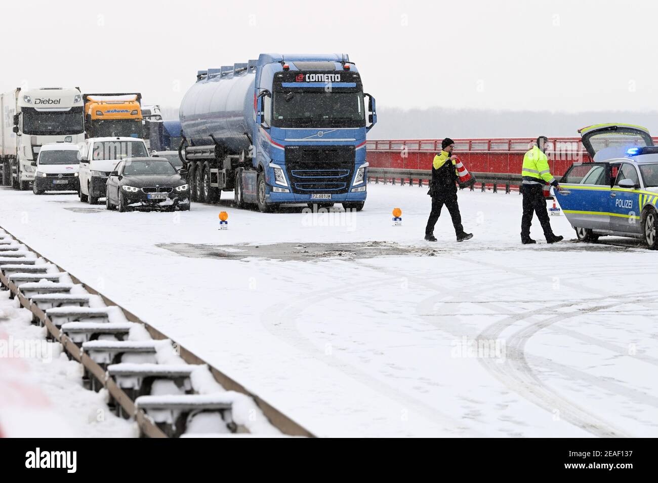 Vockerode, Deutschland. Februar 2021, 09th. Polizeibeamte räumen die Barriere wieder von der Fahrbahn ab. Vollsperrung der Autobahn A9 auf der Elbbrücke bei Vockerode. Hier ist gestern Abend ein LKW in die Absturzbarriere gestürzt. Quelle: Heiko Rebsch/dpa-Zentralbild/dpa/Alamy Live News Stockfoto