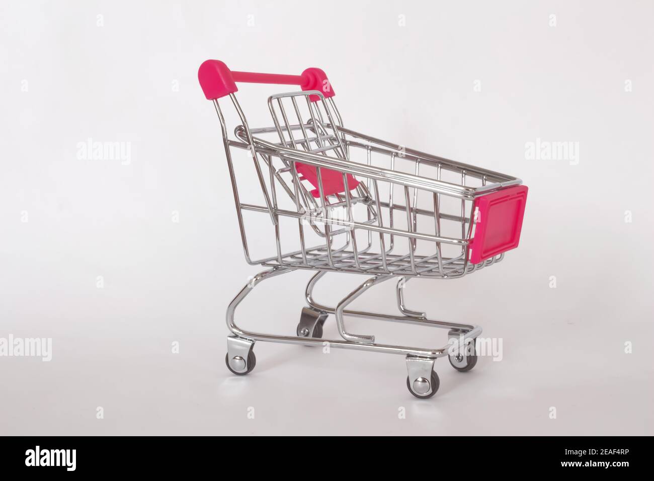 Leerer kleiner pinker Einkaufswagen oder Wagen isoliert auf weißem Hintergrund. Einkaufskonzept. Stockfoto