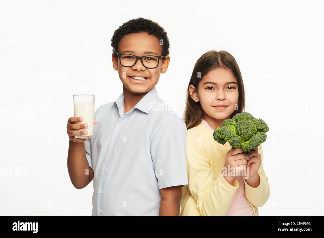 Multiethnische Gruppe von Kindern mit gesunden Brokkoli und Milch. Gesunde Ernährung von Kindern Stockfoto