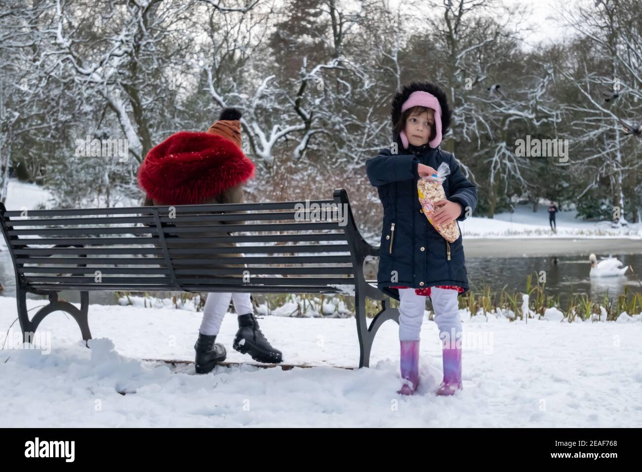 Glasgow, Schottland, Großbritannien. 9th. Februar 2021. UK Wetter: Eine Frau und ein Kind neben dem gefrorenen Teich im Queen's Park nach starkem Schneefall von Storm Darcy. Kredit: Skully/Alamy Live Nachrichten Stockfoto