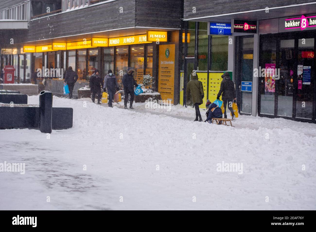 Lebensmitteleinkäufe während eines Schneesturms und covid-19 in den Niederlanden. Menschen, die im Schnee laufen Stockfoto
