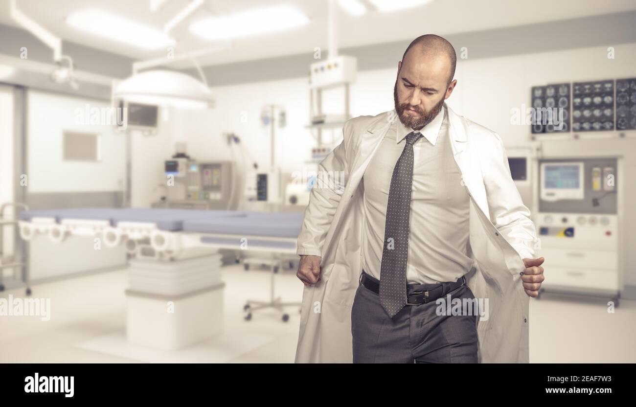 Müder Arzt zieht sein Kleid in einem Operationssaal aus. Stockfoto