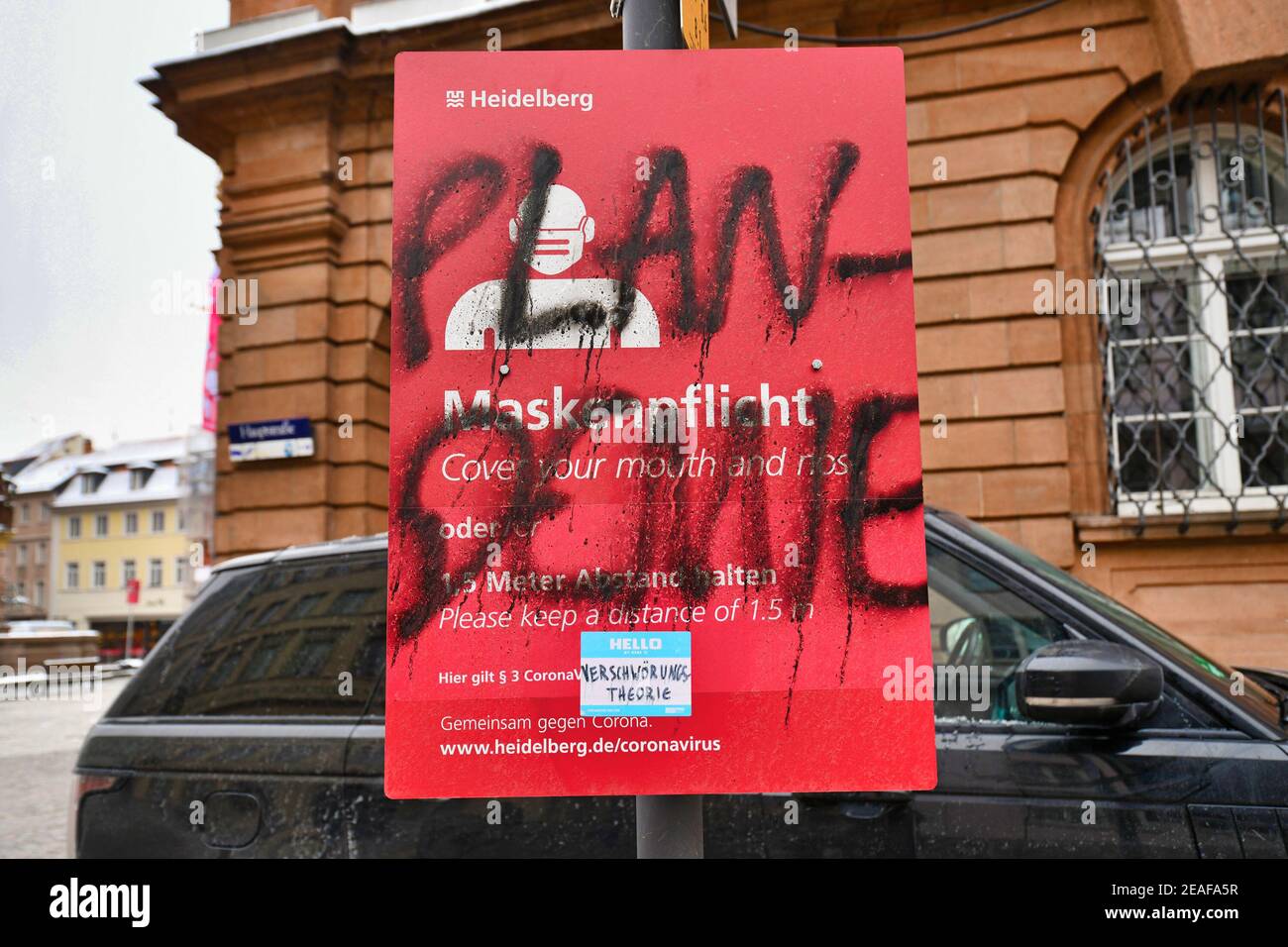 Heidelberg, Deutschland - Februar 2021: Wort 'Plandemic' auf Deutsch geschrieben über Zeichen für Gesichtsmaske und Abstand Anforderung von Verschwörungstheoretiker in p Stockfoto