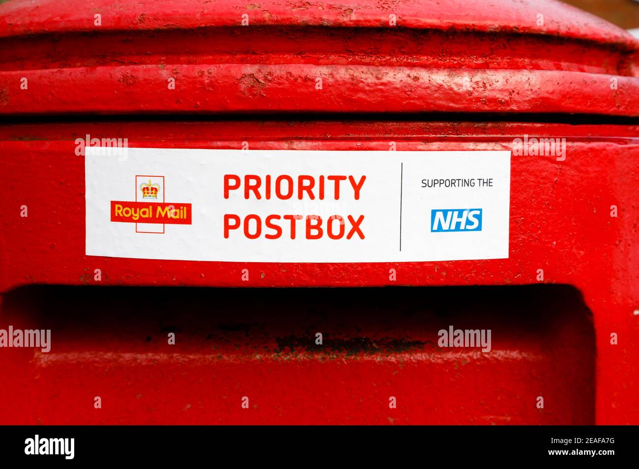 Traditionelle rote britische Royal Mail Postbox mit Aufkleber. Vorrangiges Postfach. Unterstützung des NHS während der Covid-Pandemie von 2020 2021 Stockfoto