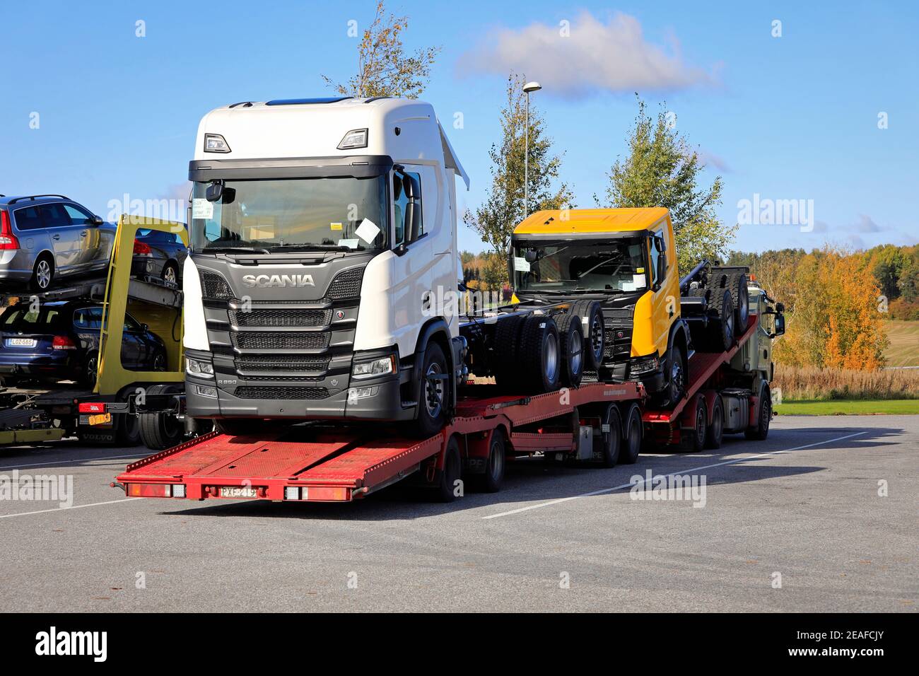 Fahrzeugträger mit zwei neuen Scania-Lkw, weiß R650 und gelb R650 XT, geparkt auf LKW-Halteplatz. Salo, Finnland. 5. Oktober 2019. Stockfoto
