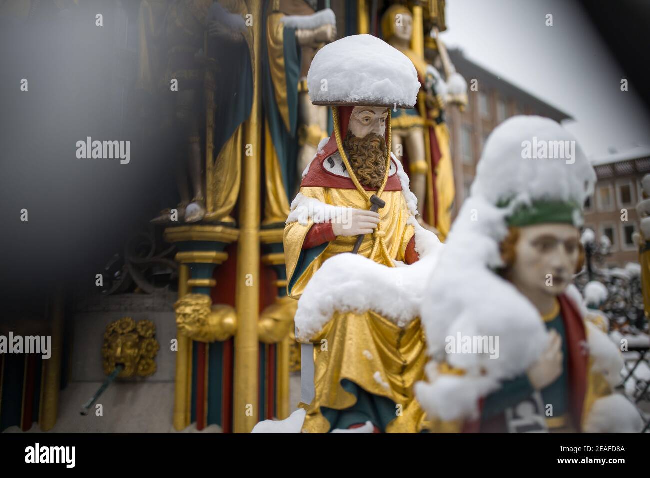 Nürnberg, Deutschland. Februar 2021, 09th. Die Figuren auf dem "schönen Brunnen" auf dem Hauptmarkt in der Altstadt sind mit Schnee bedeckt. Die Figuren sollen die Weltanschauung des Heiligen Römischen Reiches im Mittelalter darstellen. Der schöne Brunnen wurde auf Wunsch von Kaiser Karl IV. Im letzten Jahrzehnt des 14th. Jahrhunderts erbaut. Quelle: Daniel Karmann/dpa/Alamy Live News Stockfoto