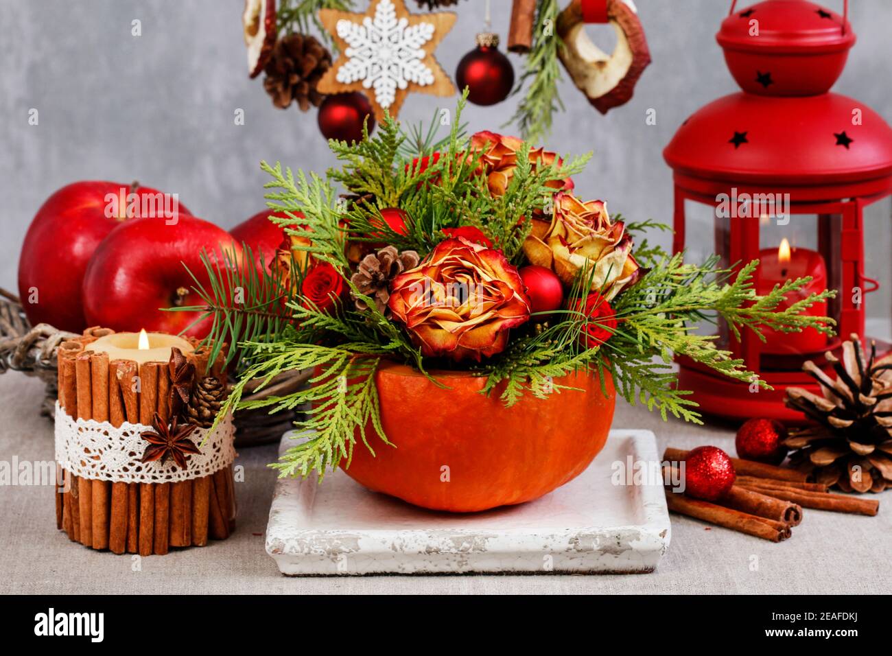 Langlebige Weihnachtsdekoration aus getrockneten Rosen, Tannenzweigen und Kugeln. Blumenarrangement im Kürbis. Natürliche Dekorationsideen. Stockfoto