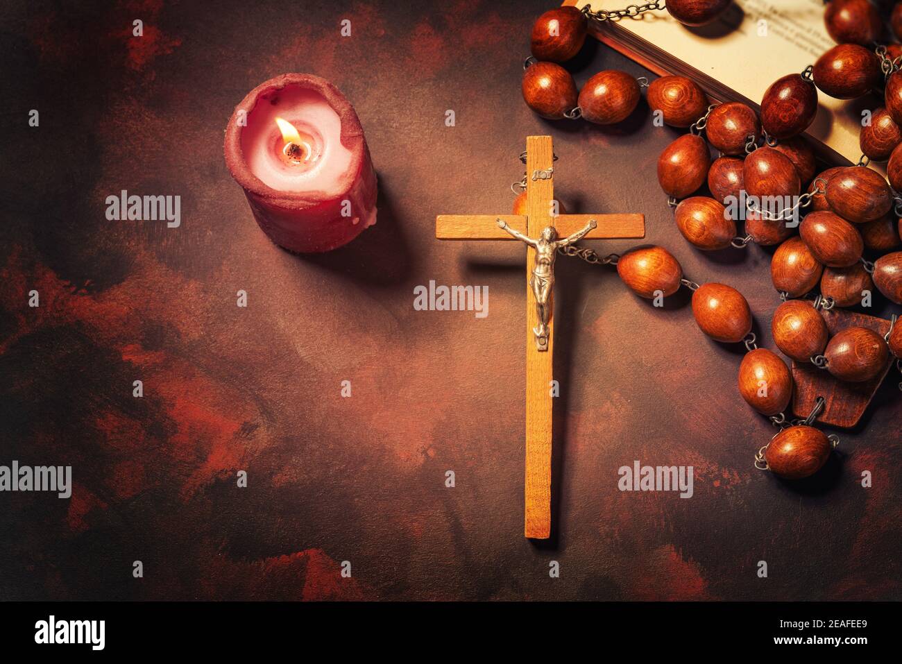 Große hölzerne Rosenkranz Perlen und Kruzifix Kreuz mit jesus, rote Kerze und bibel Buch, spirituelle Atmosphäre, Religion Konzept. Stockfoto