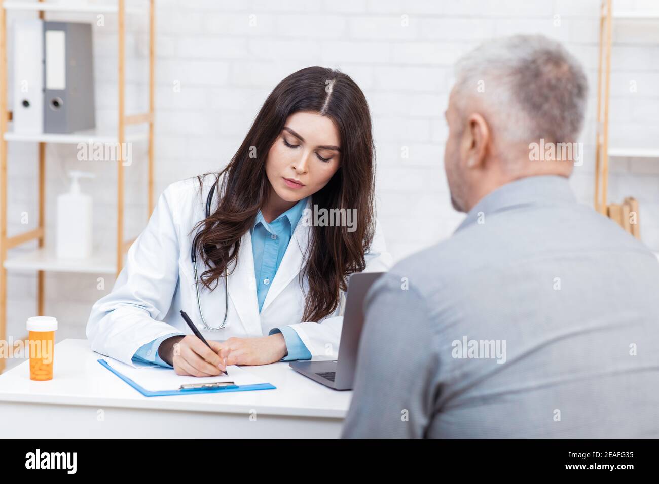 Senior Mann Besuch Arzt in modernen Büro-Interieur Stockfoto