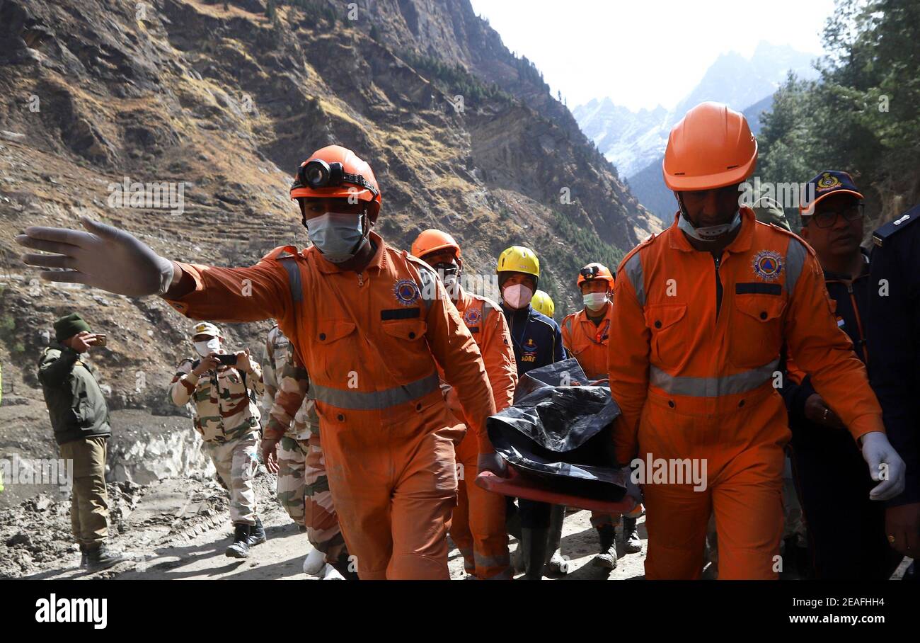 Dehradun. Februar 2021, 9th. Rettungskräfte tragen die entnommene Leiche eines Opfers in der Nähe des Wasserkraftprojekts Dhauliganga, nachdem ein Gletscherausbruch im Bezirk Chamoli im nördlichen hügeligen indischen Bundesstaat Uttarakhand am 9. Februar 2021 stattfand. Die Zahl der bisher aus den betroffenen Gebieten geborgenen Leichen ist auf 32 gestiegen, von denen noch nur sieben identifiziert werden konnten, bestätigte ein hochrangiger staatlicher Polizeibeamter. Quelle: Str/Xinhua/Alamy Live News Stockfoto