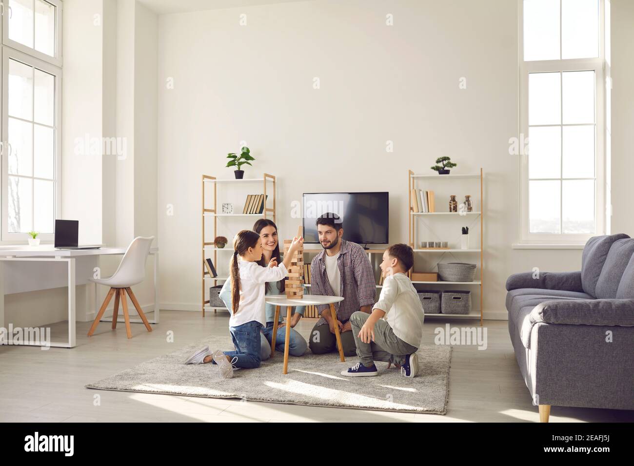 Glückliche Familie Vater Mutter und zwei Kinder sitzen auf dem Boden Und zu Hause spielen Stockfoto