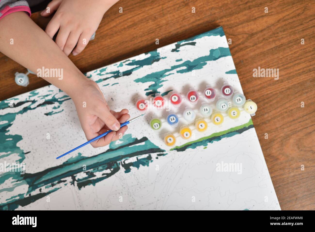 Das Kind zeichnet ein Bild mit Acrylfarben mit einem Hinweis durch Zahlen Stockfoto