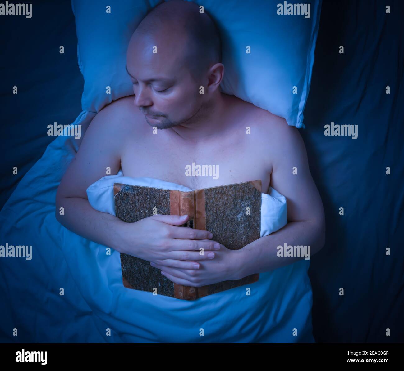 Mann schläft im Bett, nachdem er ein Buch gelesen hat. Stockfoto