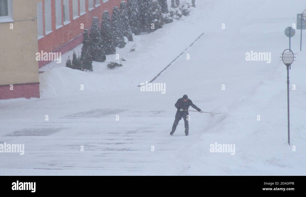 Eine Person entfernt im Winter Schnee in einem Schneesturm, arbeitet mit einer Schaufel Stockfoto